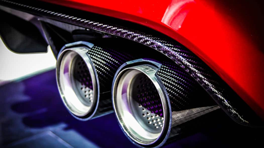 Hinter dem Poser-Lärm steckt die Autolobby Zwei Auspuffrohre von einem roten Auto in Nahaufnahme