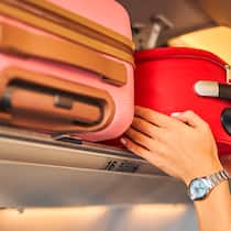 Extragebühren fürs Handgepäck sollen fallen 2D80JFB Hands laying down a carry-on baggage on an upper shelf