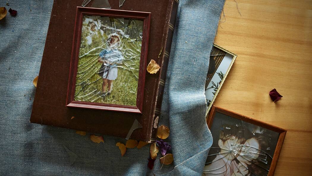 Sexueller Missbrauch an unter 16-Jährigen soll nicht mehr verjähren Ein Bild in einem Bilderrahmen mit zerbrochenem Glas liegt auf einem Tisch, auf dem Bild sieht man eine Person.