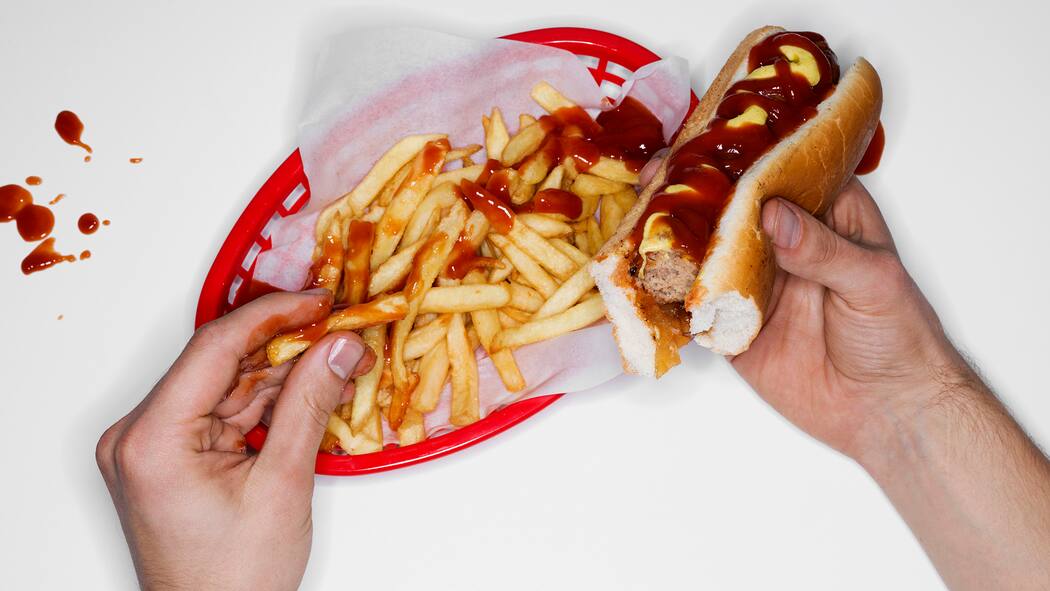 Ungesunde Snacks machen süchtig wie Zigaretten Eine Person isst Pommes Frittes und Burger. Chips, Tiefkühlpizza und Softdrinks können nicht nur krank machen. Sondern auch süchtig.