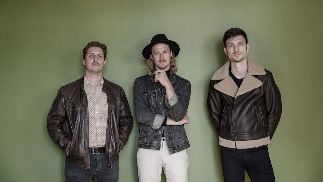 Schweizer Band findet KI-Fakes von eigenen Songs Die drei Sänger der Schweizer Band Bell Baronets vor einer grünen Wand