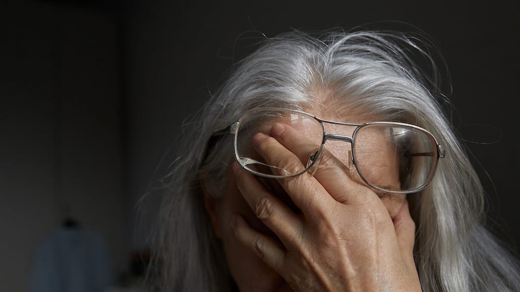 Männer und Frauen stehen gleich schlecht da Eine Seniorin hält sich die Hand vors Gesicht