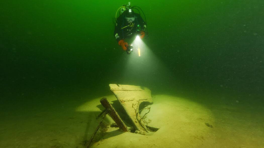 Das gilt, wenn Sie sich auf Schatzsuche begeben Taucher beleuchtet ein versunkenes Schiffsteil im Zürichsee