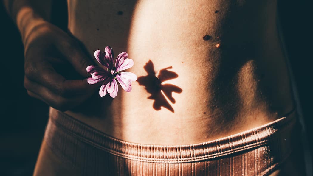 Analysen des Mikrobioms – was bringt das? Bauch einer jungen Frau mit einer Blume. In der Schweiz leiden Hunderttausende am schmerzhaften Reizdarmsyndrom. Labors bieten sinnlose Tests der Darmbakterien an.Was stattdessen helfen kann.