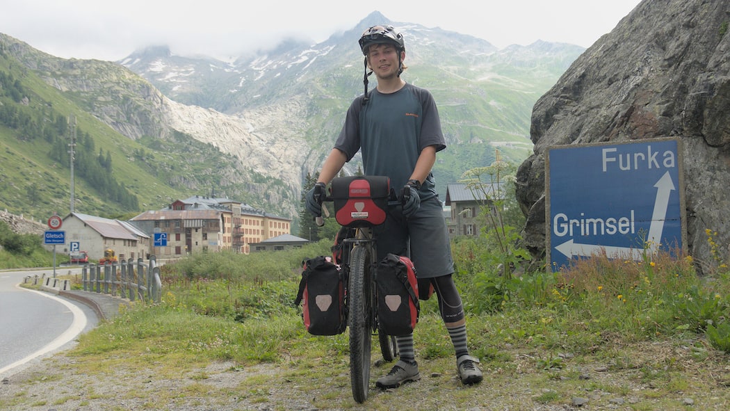 Die wahre Tour de Suisse Joel von Rotz in Gletsch, mit Sicht zum Furkapass und Rhonegletscher. Velotour durch die ganze Schweiz.