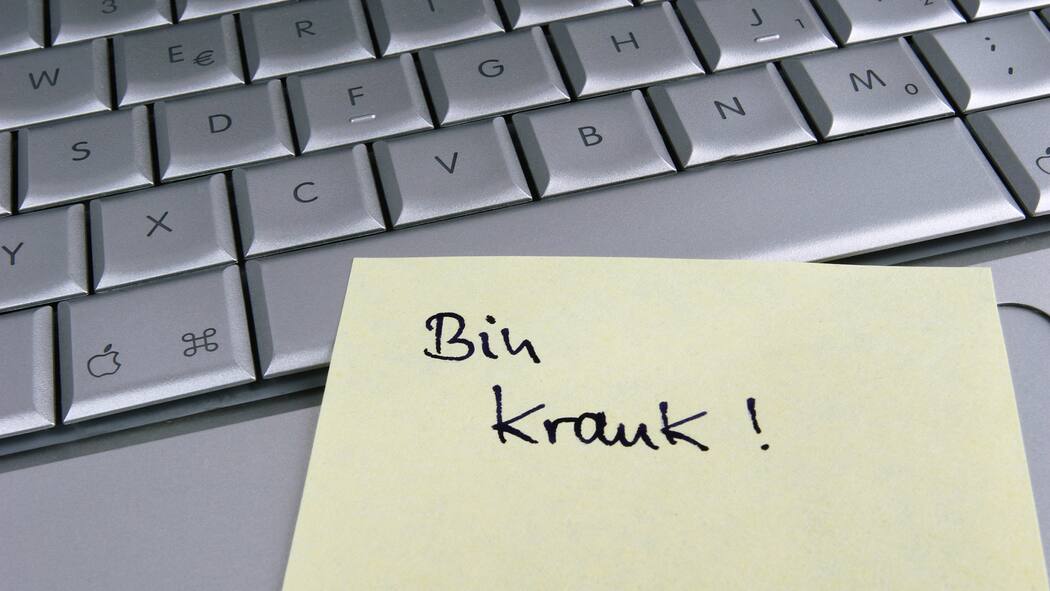 Auch bei Krankschreibung droht nun Kündigung Ein Zettel klebt an einer Tastatur mit der Aufschrift: Bin krank!