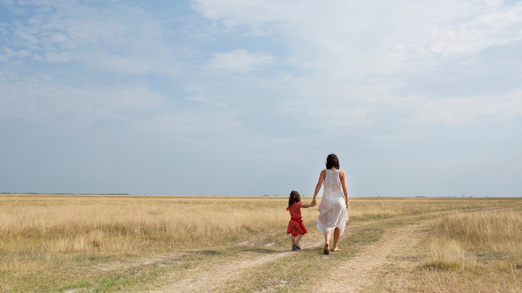 Immer mehr Eltern schlittern ins Burn-out: Hier finden sie Hilfe 30-40 jhrige Mutter mit 4-6 jhrigen Kind geht Hand in Hand einen Feldweg entlang
