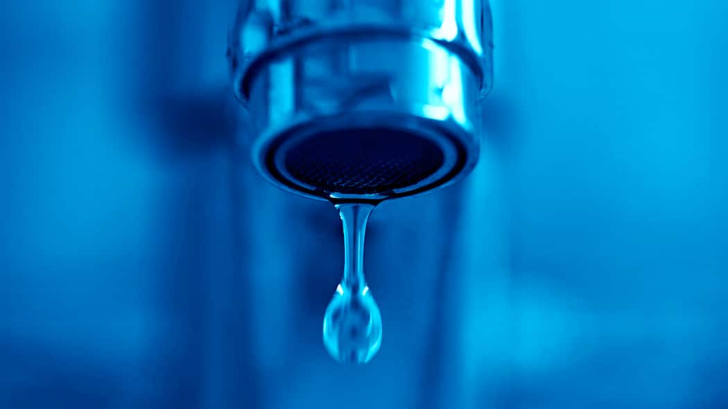 Wer muss die Reparatur bezahlen? Ein tropfender Wasserhahn vor blauem Hintergrund. Was rechtlich zum kleinen Unterhalt in der Mietwohnung zählt.