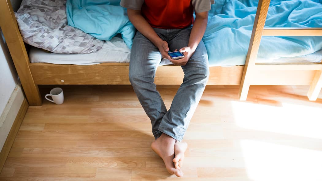 Geflüchtete müssen ihre Handys jetzt durchsuchen lassen Ein unbegleiteter minderjähriger Asylsuchender (UMA) blickt auf sein Handy.