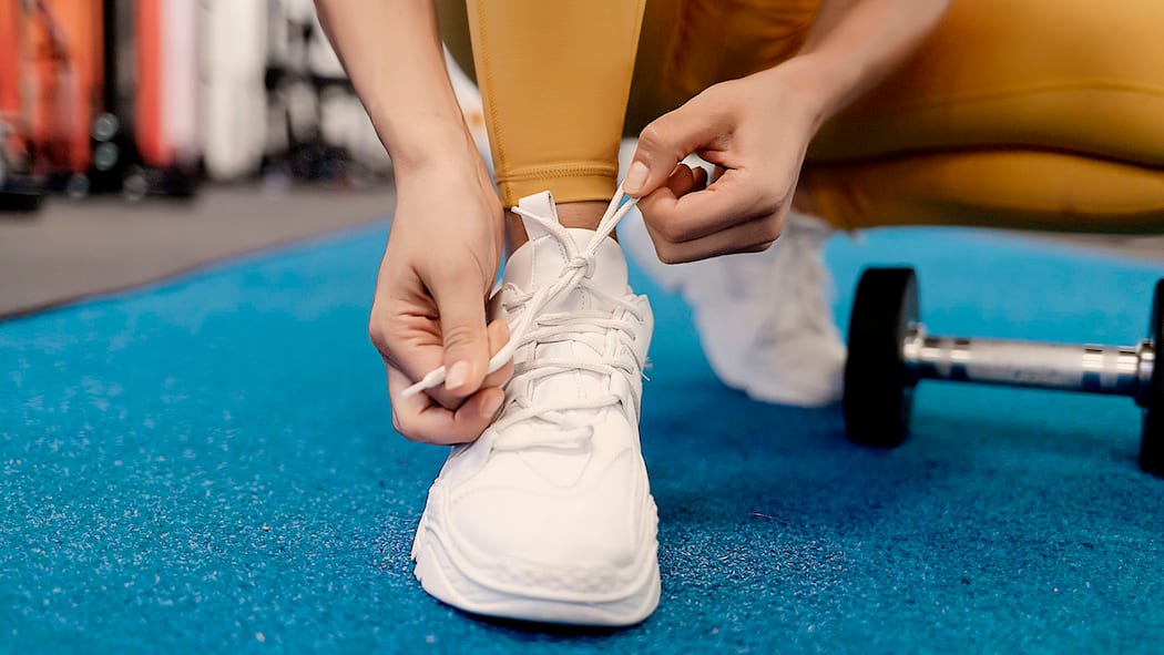 Fit und mit Struktur durch den Alltag Close up front view of woman's hands tying shoelaces on sneakers in the gym.
1327976780