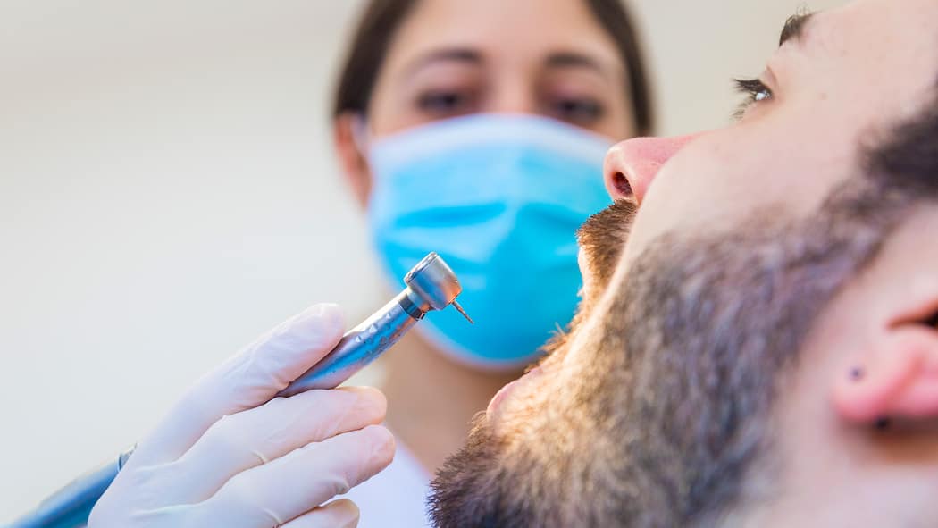 Zahnarztkosten sparen – so gehts Eine Zahnärztin setzt bei einem Patienten zum Bohren an.