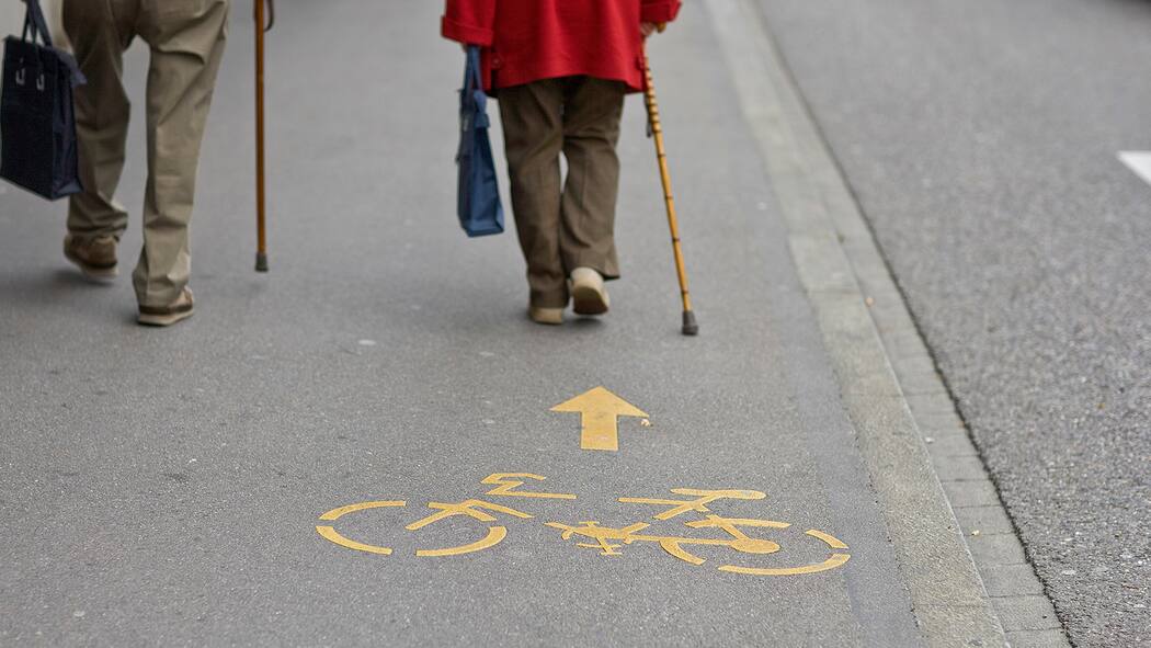 Velofahrer gegen Fussgänger gegen Autofahrer Ältere Fussgänger blockieren die Fahrbahn auf Veloweg