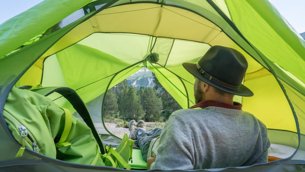 Einfach das Zelt aufstellen, gut ist? Wo das noch möglich ist Mann blickt aus dem Zelt: Einfach irgendwo das Zelt aufzuschlagen, ist vielerorts verboten. Eine Übersicht zeigt, in welchen Kantonen es verboten ist und was wo erlaubt ist