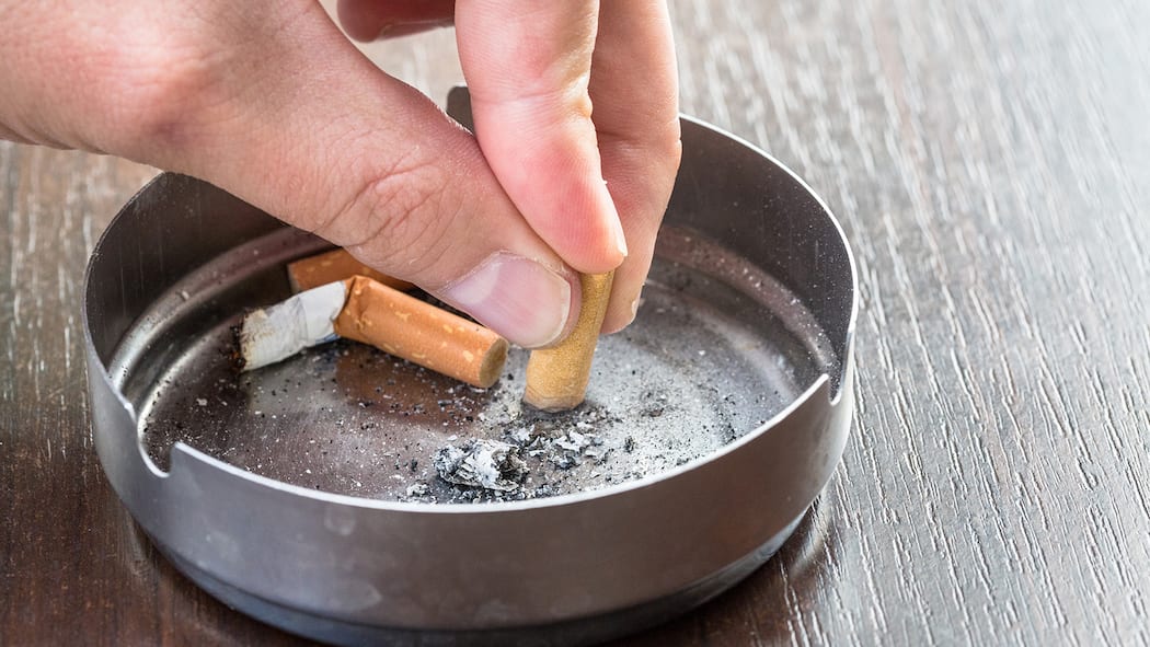 Jetzt ist Schluss Ein Mann drückt die letzte Zigarette aus, bevor er aufhört zu rauchen.