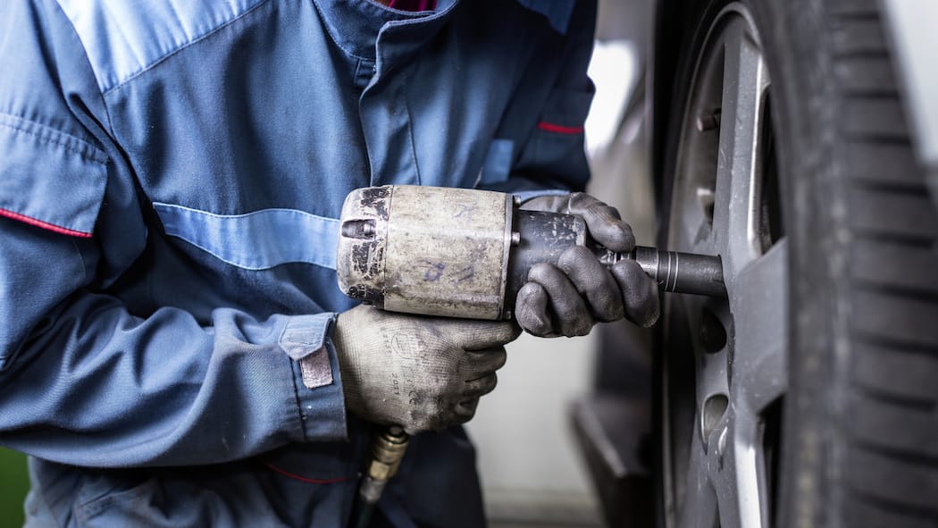 Enorme Preisunterschiede bei Garagen Ein Automechaniker wechselt einen Reifen an einem Auto.