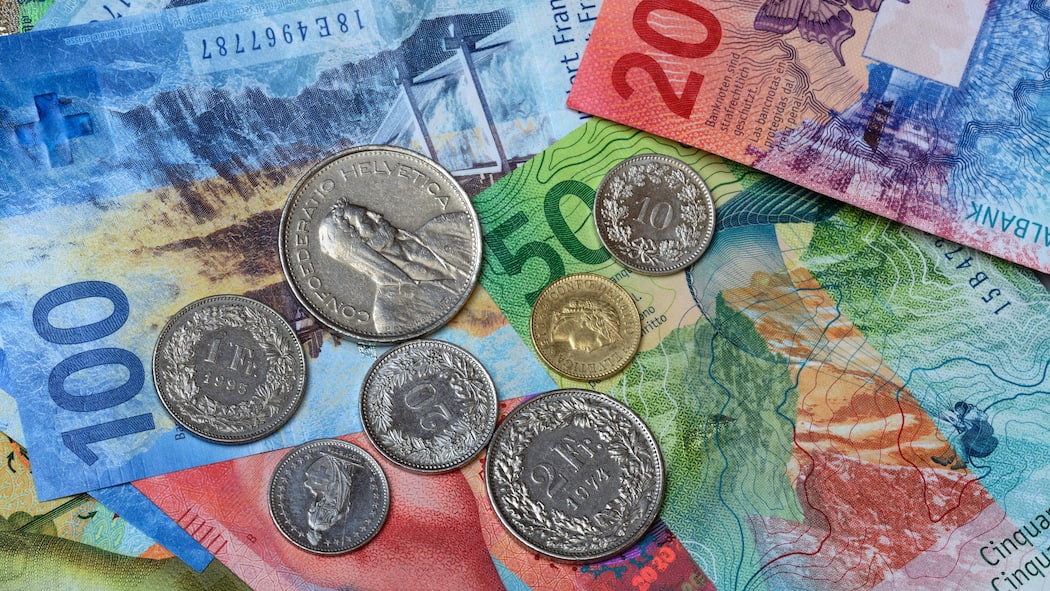 Wie viel Geld steht mir im Alter zu? Verschiedene Banknoten und Münzen liegen auf einer Oberfläche. Die Höhe der AHV-Rente bemisst sich danach, wie lange man Beiträge an die AHV gezahlt hat und wie hoch der durchschnittliche Lohn war.