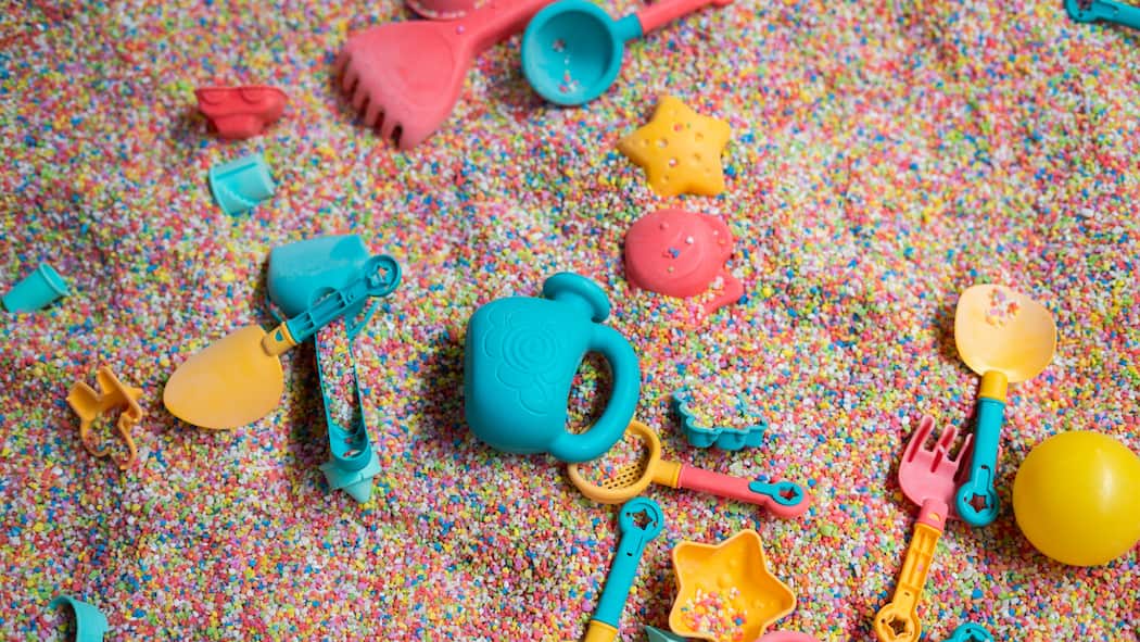 Überall lauert Gift im Plastik Farbiges Plastikspielzeug im Sand, teils vergraben