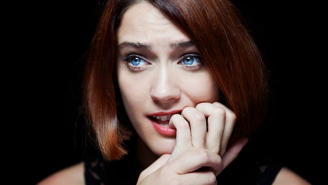 Wenn es mehr als nur Sorgen sind Eine junge Frau blickt sorgenvoll auf etwas und kaut auf ihren Nägeln herum.