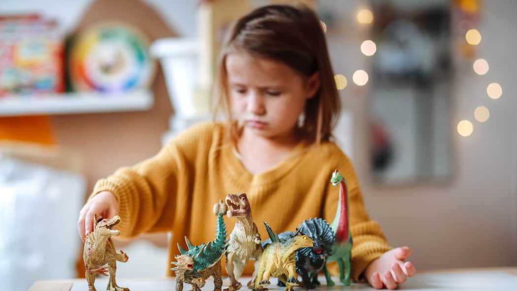 Wenn liebevolle Eltern ihre Kinder ungewollt vernachlässigen sad little girl plays with dinosaur figurines at home alone.