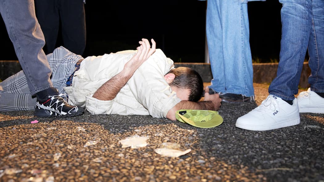 Strengere Strafen für Schläger Ein Mann liegt auf dem Asphaltboden, umringt von drei Personen, von denen nur die Schuhe zu sehen sind. Ab 1. Juli 2023 werden Gewalttäterinnen und Gewalttäter härter bestraft, insbesondere wenn die Straftat aus einer Gruppe heraus begangen wurde.