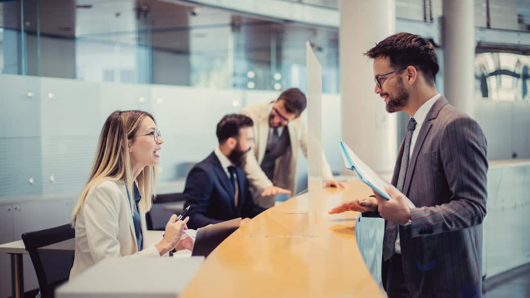 Warum die Bank sich beim Erben querstellt Eine Bankangestellte spricht mit einem Kunden, der am Tresen vor ihr steht.