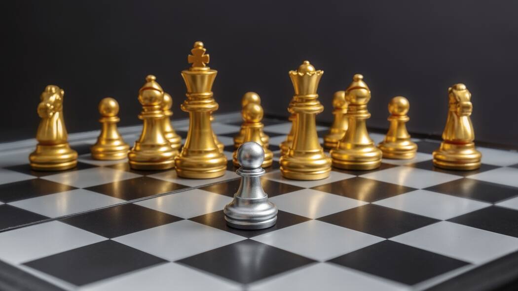 Lohnt es sich, jetzt zu investieren? Auf einem Schachbrett steht eine Grosszahl goldiger Schachfiguren einer einzelnen Figur in silberner Farbe entgegen.