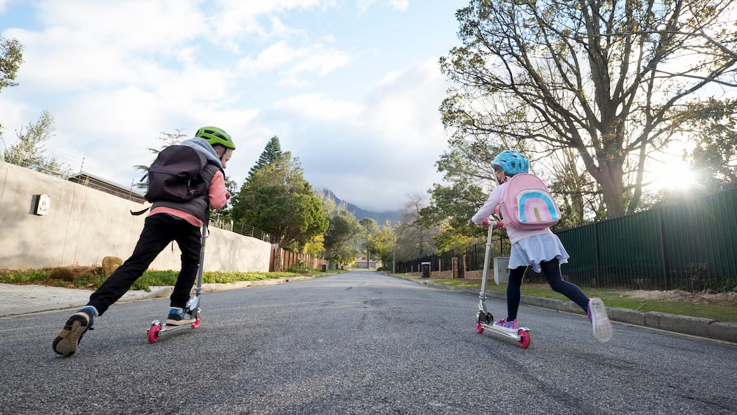 Ein grosser Schritt für Kleine Zwei kleine Schulkinder mit dem Trottinett auf dem Weg zur Schule.