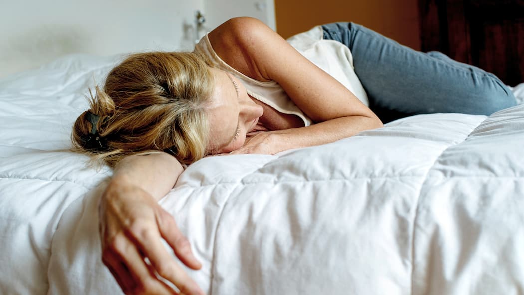 Long Covid wird Sozialwerke stark belasten Frau liegt erschöpft auf Bett