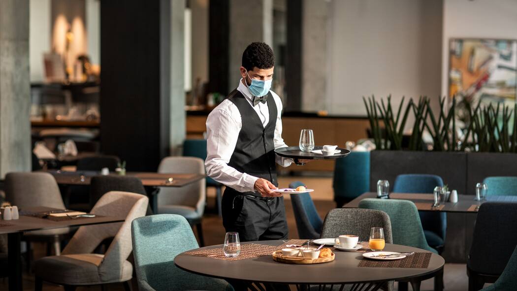 Muss ich den Gutschein akzeptieren? Ein Angestellter eines Hotels räumt alleine einen Frühstückstisch ab.