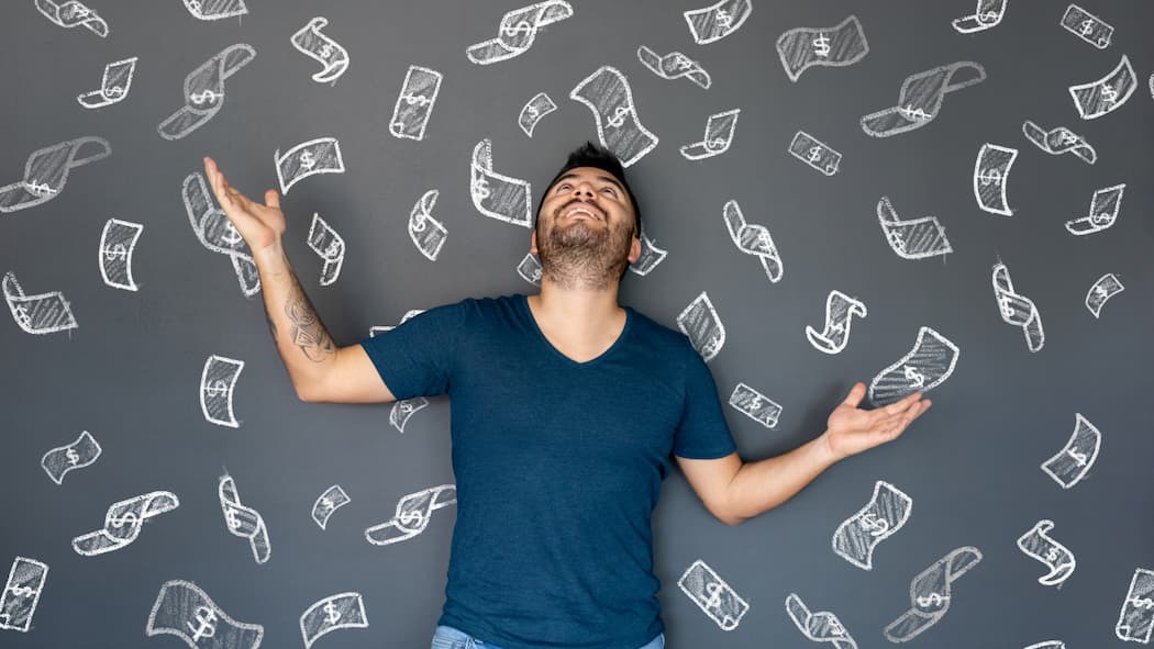 Muss ich dem Steueramt Auskunft geben? Ein Mann steht mit dem Rücken zu einer grauen Wand, auf der viele Geldscheine aufgemalt sind.