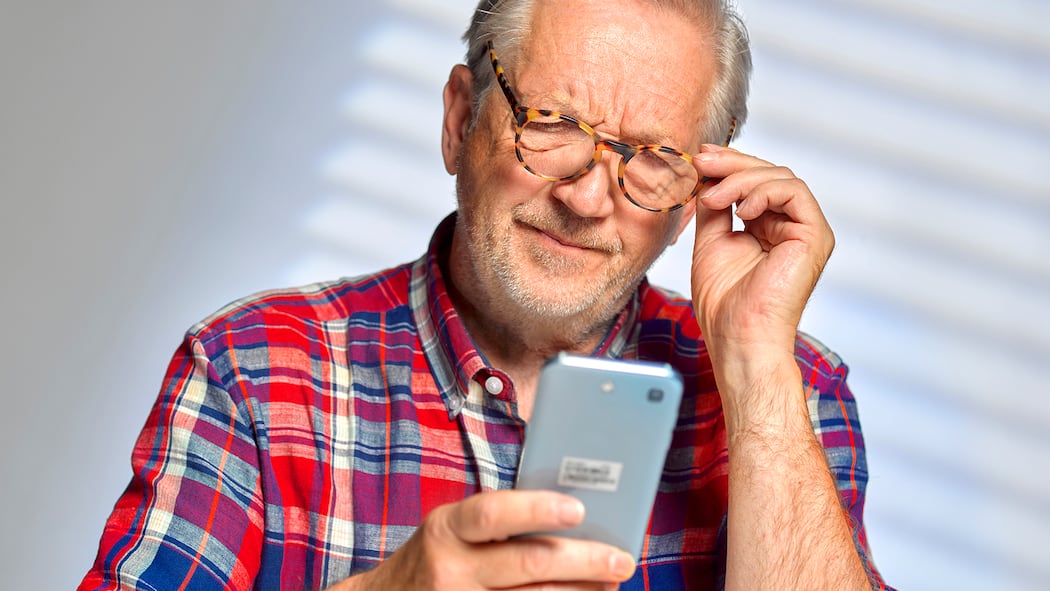 7 Übungen gegen eckige Augen Ein älterer Mann schaut angestrengt auf sein Handy.