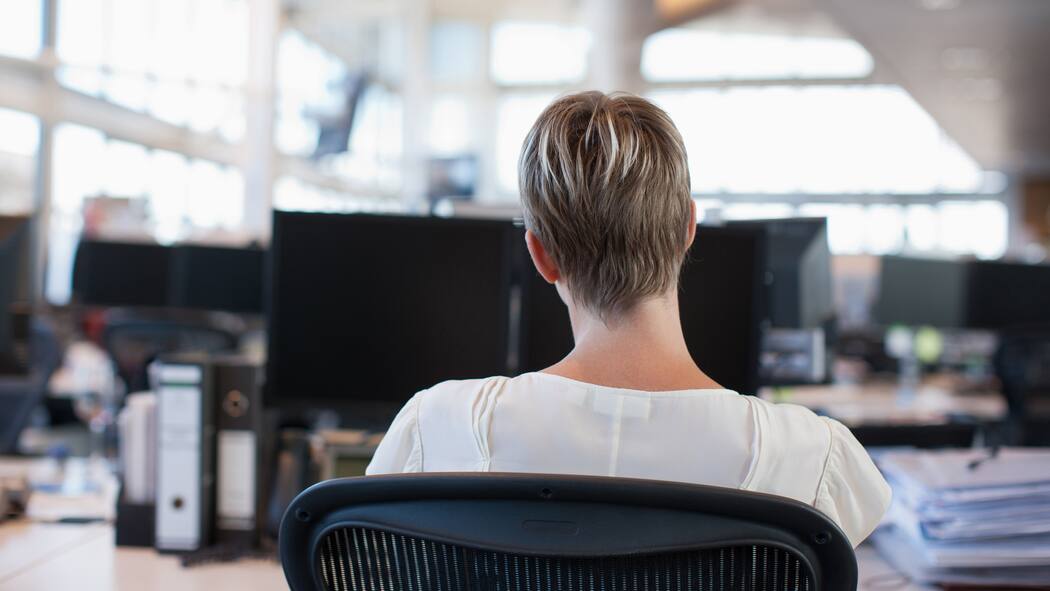 Muss ich jetzt ins Büro? Eine Mitarbeiterin sitzt in einem Grossraumbüro vor einem Computerbildschirm.