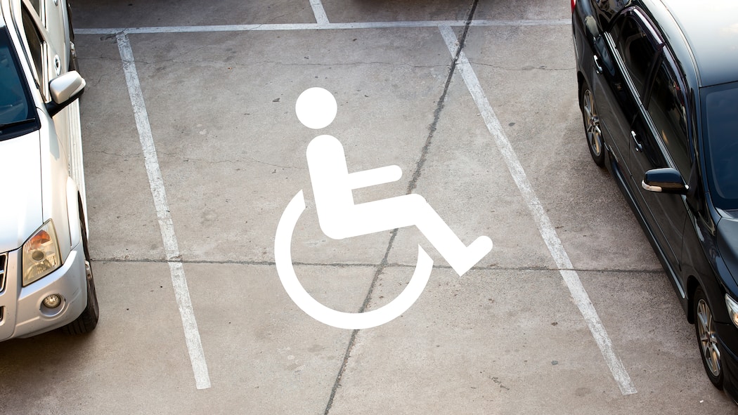 Das Kreuz mit dem Rotkreuz-Fahrdienst Rollstuhl-Logo auf Parkplatz