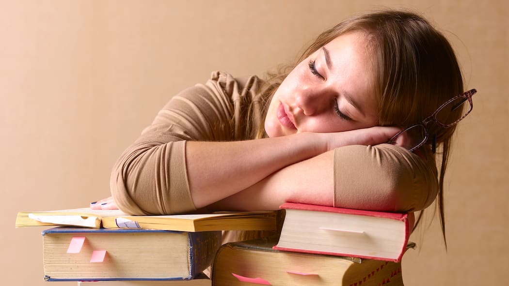 Klüger über Nacht Eine junge Frau schläft, auf einen Stapel Bücher gelehnt.