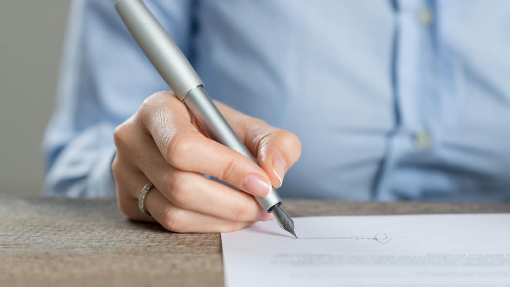 Vollmacht unterschreiben – darauf sollten Sie achten Eine Frau unterschreibt ein Formular für eine Vollmacht. Welche Arten von Vollmacht es gibt und welche Folgen sie haben.