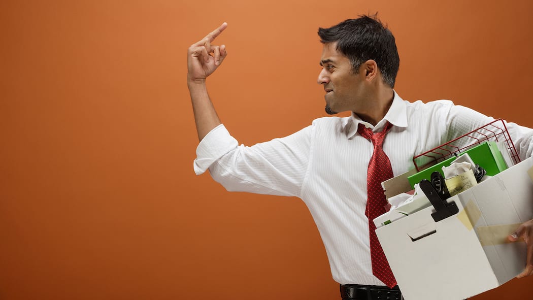 Ist eine mündliche Kündigung gültig? Ein Mann zeigt wütend den Stinkefinger, während er seine Arbeitsstelle verlässt.