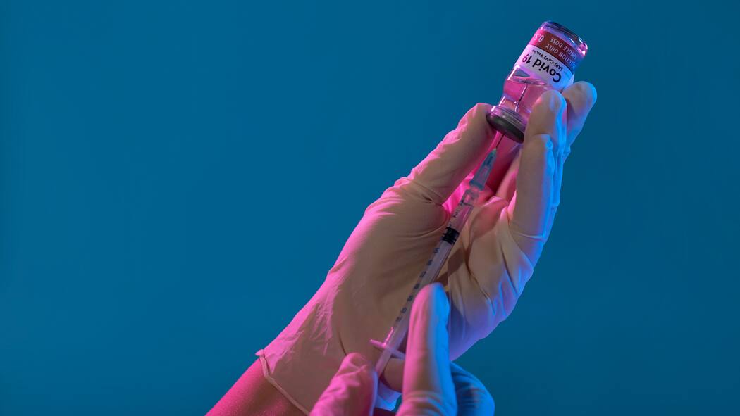 Schwer geschädigt – wen interessierts? Bild einer medizinischen Fachperson, die eine Dosis eines Corona-Impfstoffs in einer Spritze aufzieht.