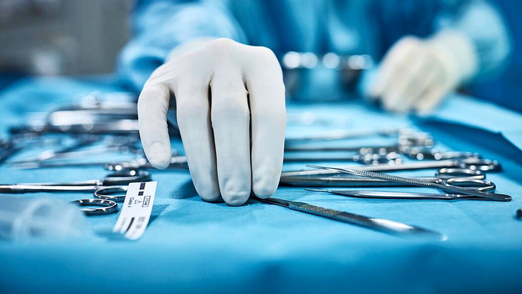 Schmerzen nach der Operation – was tun? Chirurg greift nach chirurgischen Instrumenten