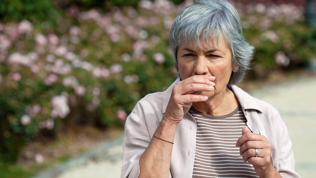 Alter schützt vor Allergien nicht Eine Frau geht an einer Blumenrabatte vorbei und muss niesen.