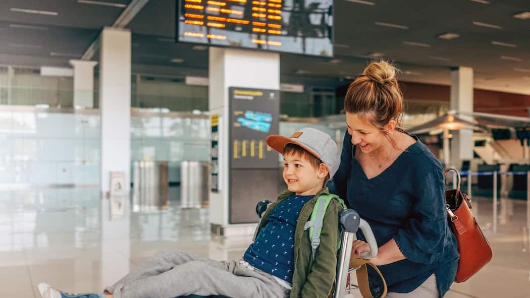 So kommen Sie stressfrei mit Kindern durch die Passkontrolle Frau mit Kind auf dem Kofferwagen am Flughafen - In den Sommerferien reisen viele ins Ausland. Wenn dabei ein Elternteil mit Kindern alleine unterwegs ist oder einen anderen Nachnamen hat, sind zusätzliche Dokumente wichtig