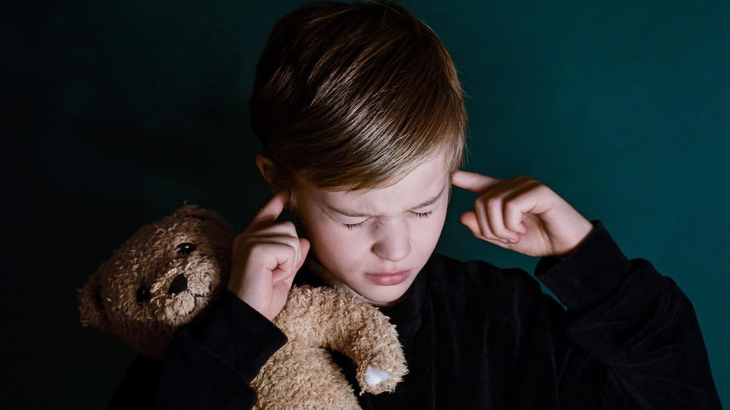 Das Leiden der Scheidungskinder Kind mit Teddybär im Arm hält sich Ohren zu