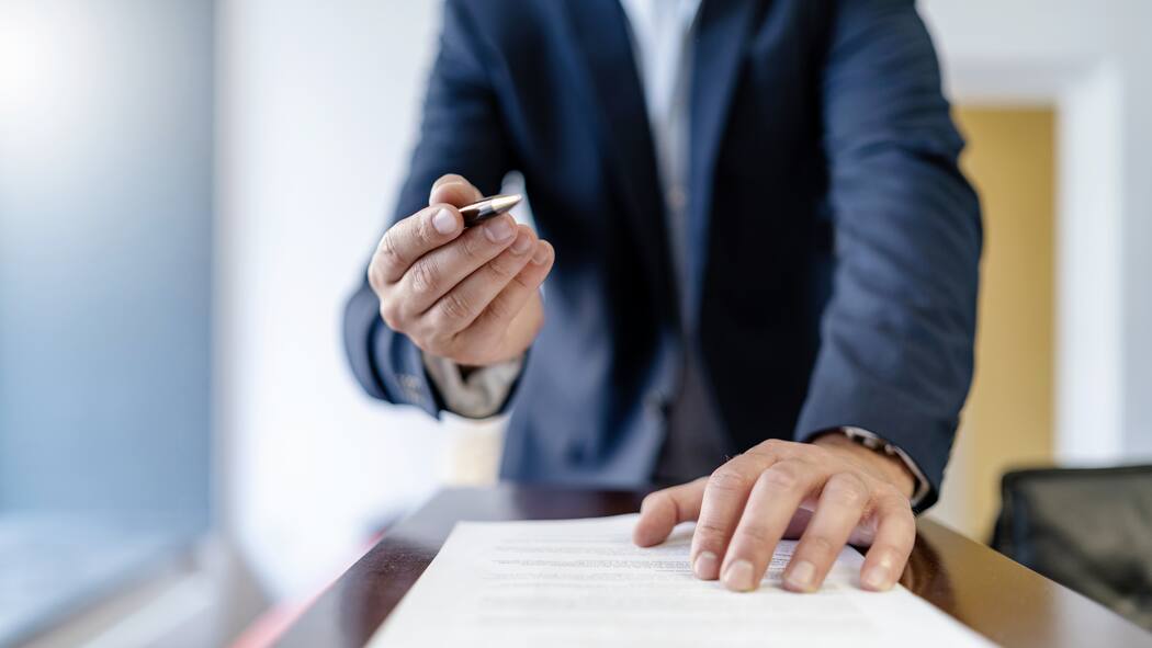 Diese Unterschrift wird sehr teuer Close-up of businessman in office presenting ballpen and contract