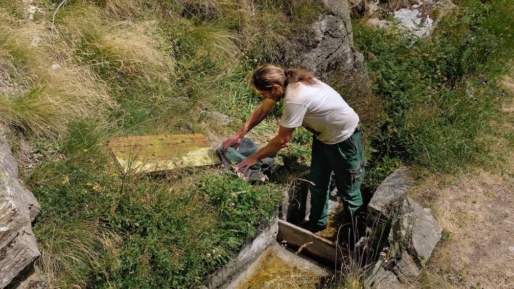 Wie Walliser Landwirte mit uralten Traditionen den Wassermangel lindern Daniel Wismer steckt einen Schieber um und leitet Wasser zu den Spritzen auf seinem Land.