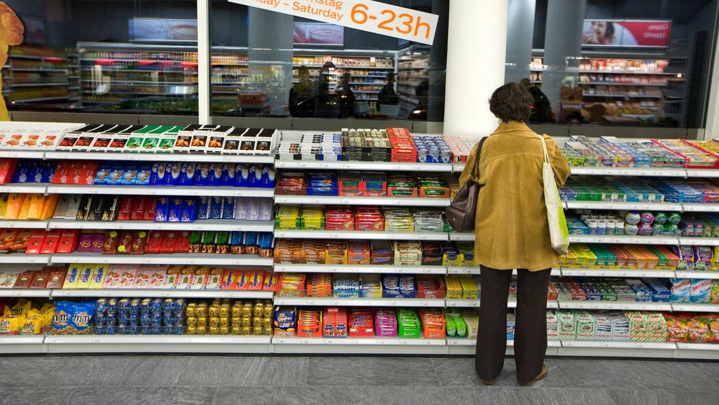 Wie Coop und Migros ihre Preise hoch halten Eine Frau steht vor einem Verkaufsregal mit Schokoriegeln in einem Coop-Pronto. Die Preise der beiden grössten Detailhändler Coop und Migros sind oftmals identisch. Schreiben sich die beiden Riesen bei den Preisen etwa ab?