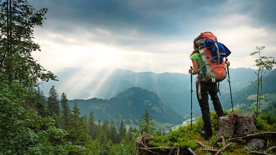 Unfall beim Wandern – wer haftet? Ein Wanderer in der Rückansicht schaut von einem Berg ins Tal. Wer haftet, wenn Wanderer verunfallen oder Schaden verursachen.