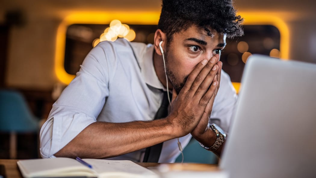 Was verheissen diese Transaktionen? Ein junger Mann schaut geschockt und irritiert in einen Bildschirm und hat dabei seine Hände wie zu einem Gebet vor seinen Mund gelegt.