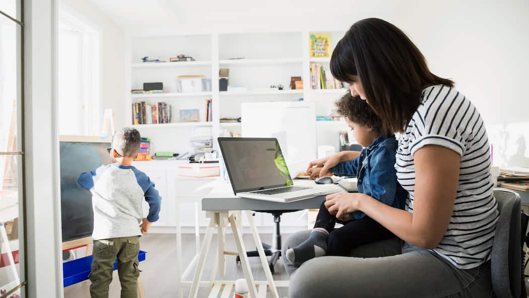 Alle Aufmerksamkeit beim Jüngsten Eine Mutter spielt mit ihrem jüngsten Kind während das ältere sich alleine beschäftigt
