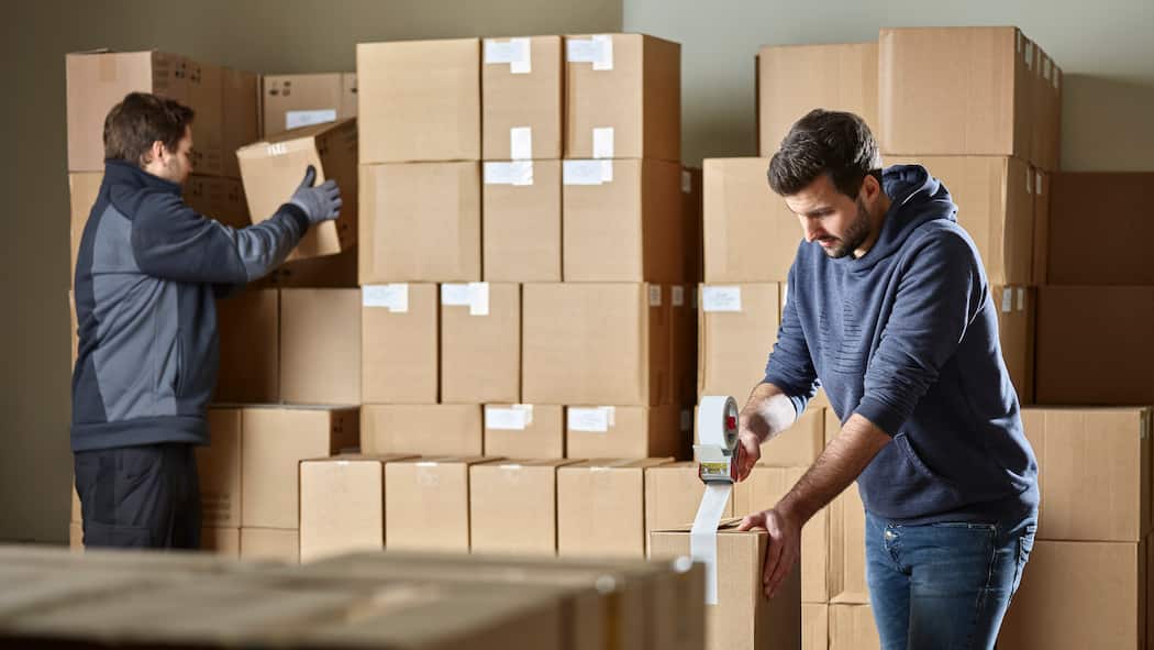 Kann ich eine beliebige Stelle ablehnen? Ein Helfer unterstützt einen anderen Lagerist beim Verpacken von Paketen.
