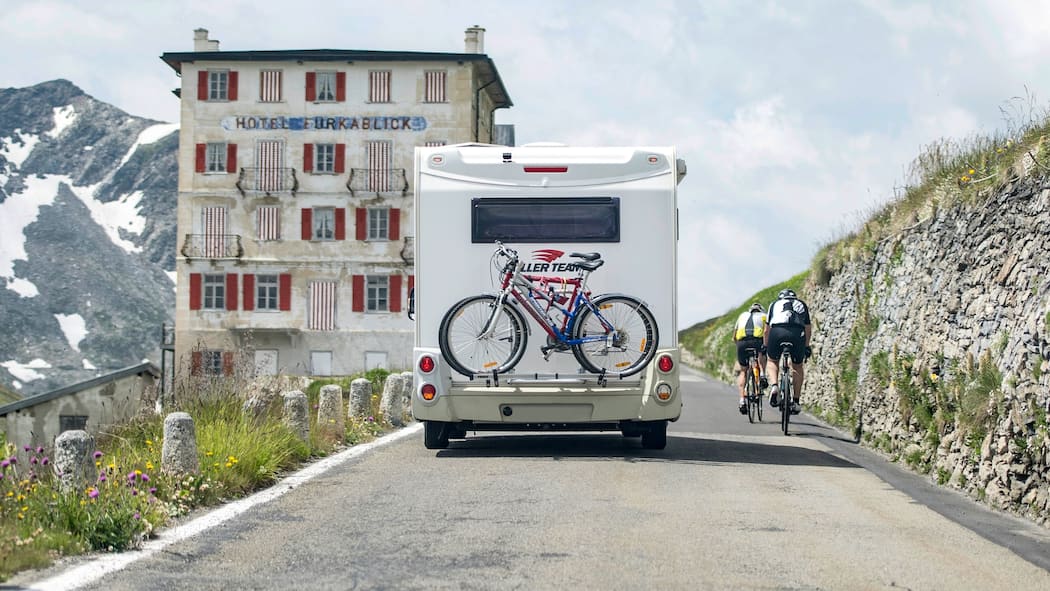 Im Ausland mieten, in der Schweiz fahren Ein Wohnmobil überholt auf der Passstrasse des Furka zwei Velofahrer.