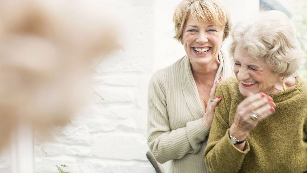 Genügt eine Vollmacht für Mutters Finanzen? Eine Frau mittleren Alters herzt eine ältere Dame.